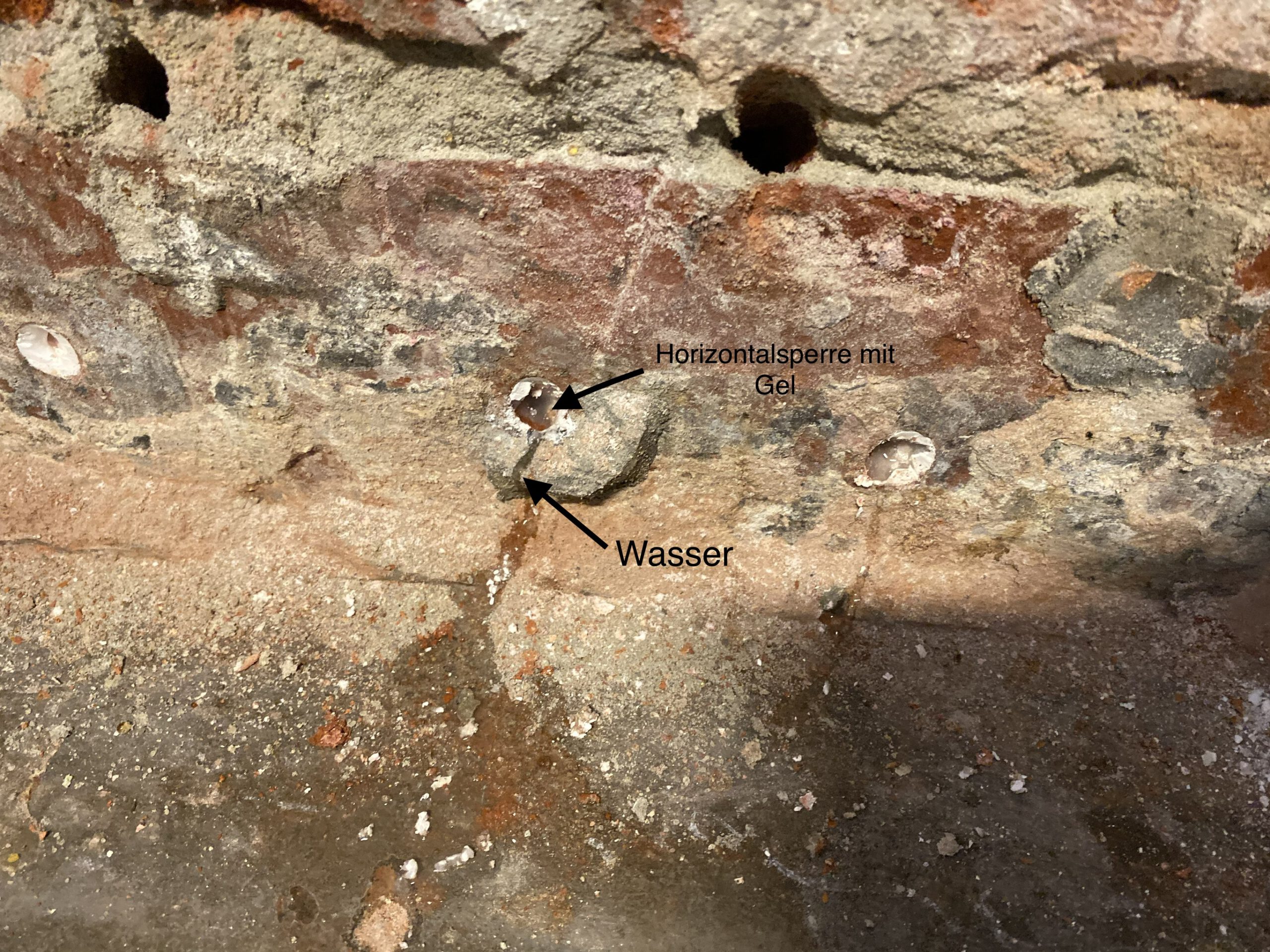 Injektionsbohrung mit Gel im Mauerwerk – Wasser tritt trotz angeblicher Horizontalsperre weiterhin aus
