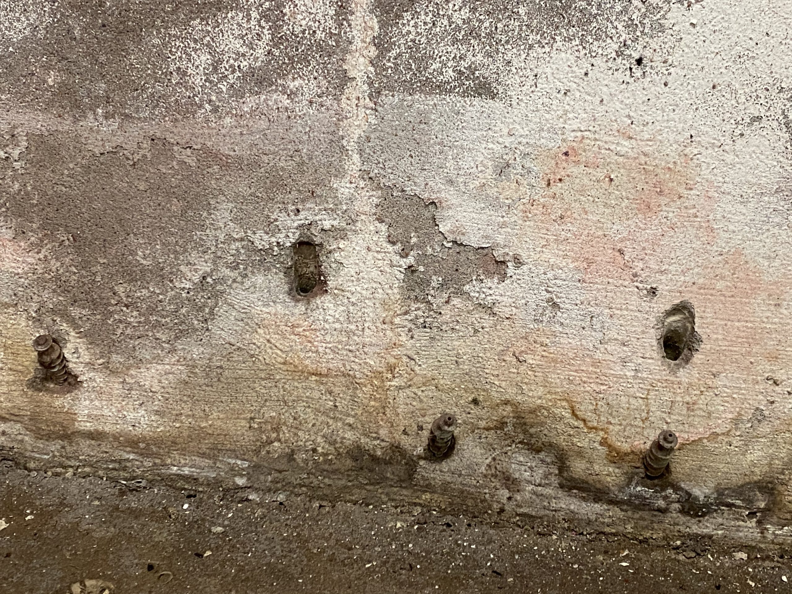 Bohrlöcher und anhaltende Feuchtigkeit in Kellerwand nach fehlgeschlagener Abdichtungsmaßnahme