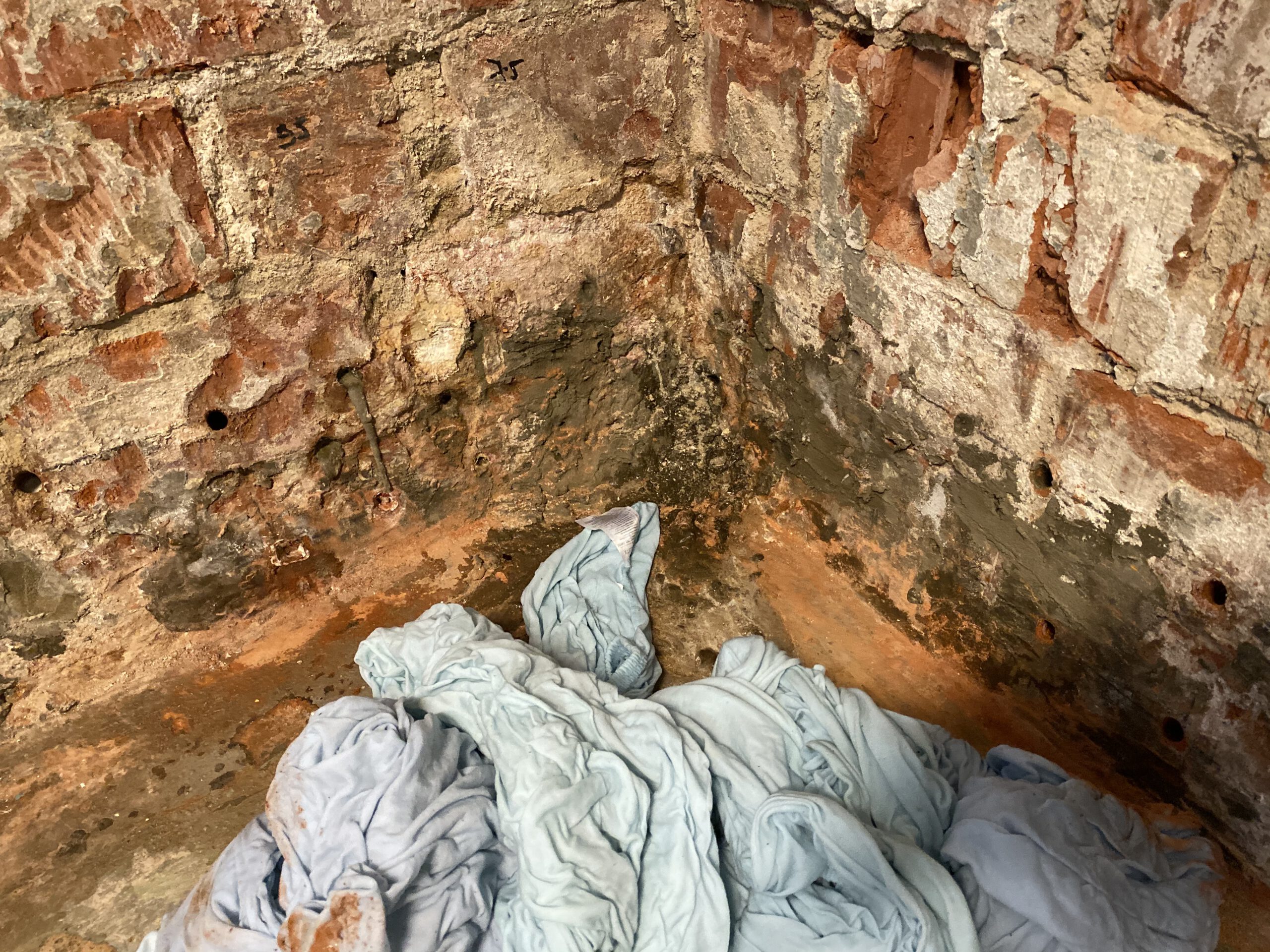 Nahaufnahme einer feuchten Kellerwand mit sichtbaren Injektionsstellen und deutlichen Schadensspuren – typisches Bild nach misslungenen Maßnahmen.