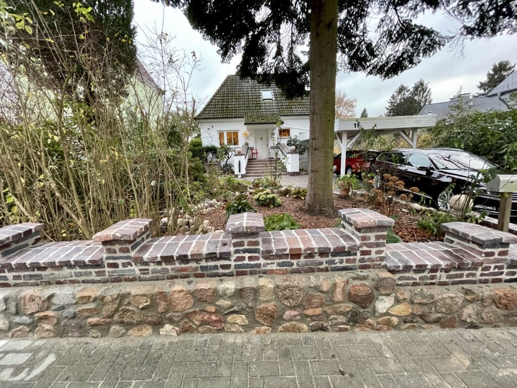 Altbausanierung mit restaurierter Natursteinmauer, wiederverwendeten Materialien und handwerklicher Reparatur historischer Bausubstanz