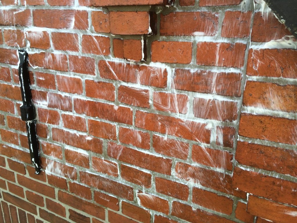 Auf dem Bild ist eine Rotsteinfassade nach Fassadenreparatur und Imprägnierung zu sehen. Durch die Behandlung wird die Wasseraufnahme der Fassade reduziert, während Aussehen und Charakter des Mauerwerks erhalten bleiben.