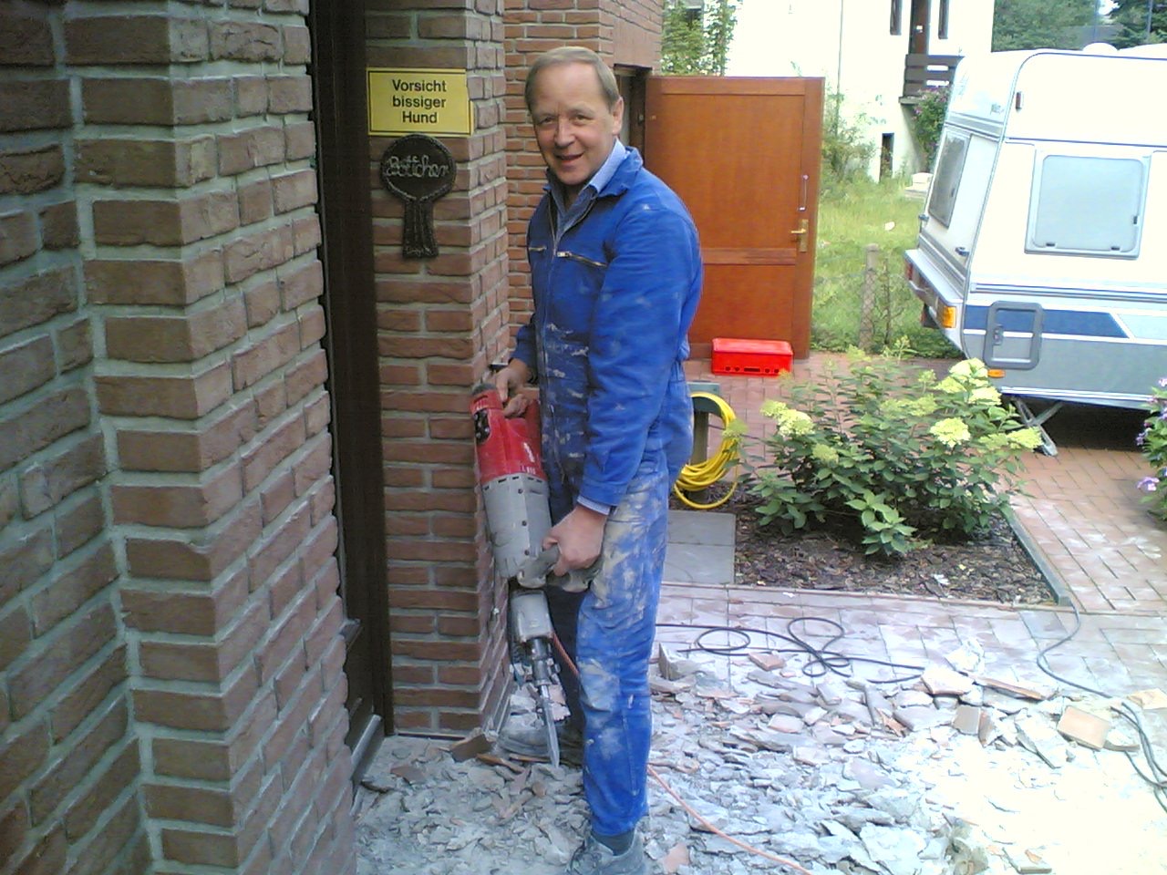 Dieter Skupch, Firmengründer von Der Hausdoktor, bei echter Baustellenarbeit mit Bohrhammer und Arbeitskleidung.